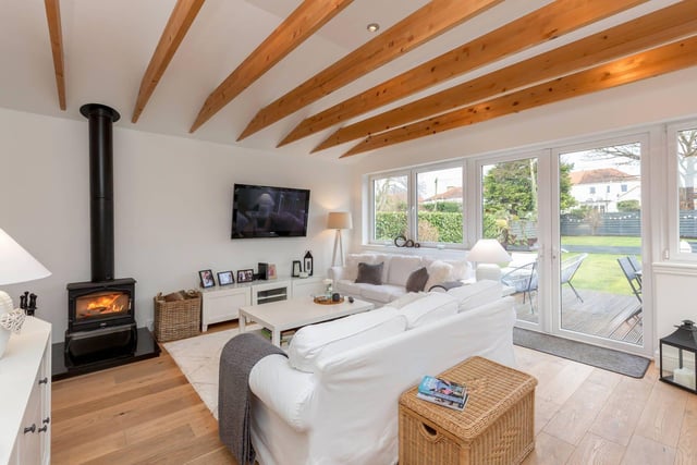 The hugely impressive family room, with wood burning stove, vaulted ceiling and exposed beams. A wall of glass floods this room with light and takes advantage of the leafy garden views.