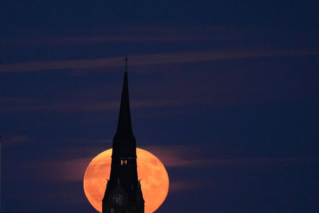 The strawberry full moon rises behind a church in Berlin, Germany, Tuesday, June 14, 2022. (AP Photo/Markus Schreiber)