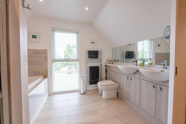 The large en-suite bathroom, which is partially tiled and boasts a double bath, dual sinks, and a separate shower.