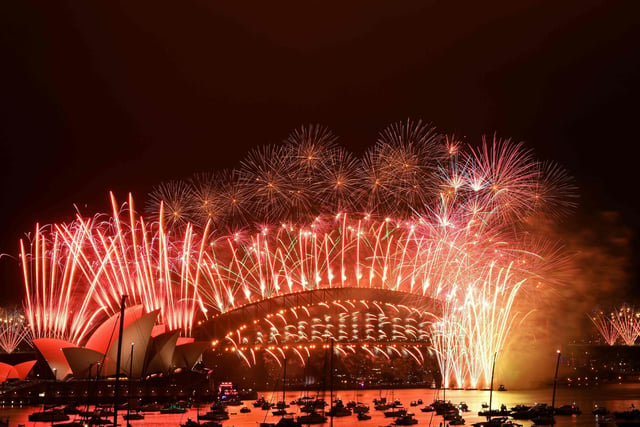 New Year's Eve fireworks erupt over Sydney's iconic Harbour Bridge and Opera House (L) during the fireworks show on January 1, 2021. (