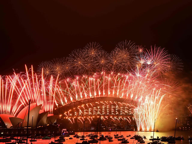 New Year's Eve fireworks erupt over Sydney's iconic Harbour Bridge and Opera House (L) during the fireworks show on January 1, 2021. (