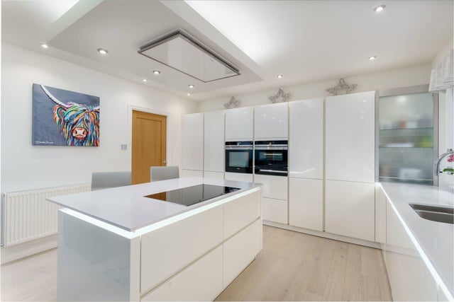 The kitchen is fitted with induction hob, oven and microwave, second oven with steamer, fridge, dishwasher and Quooker tap as well as a range of base and wall-mounted units and an island.