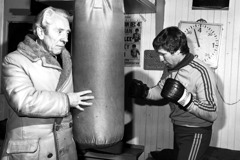Scottish boxer Ken Buchanan (in Lonsdale headgear) hits the punch-bag during a training session with his father Tommy Buchanan in March 1983.