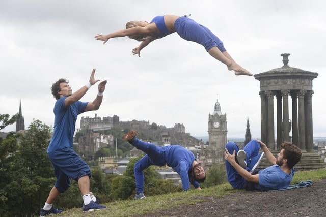 The UK's hottest circus company Barely Methodical Troupe (BMT), who performed their show SHIFT as part of the Edinburgh Fringe Festival 2018 at Underbelly's Circus Hub on the Meadows, perform some of their acrobatics on the top of Calton Hill with Edinburgh Castle and the Balmoral clock in the background.  Guys on the ground left to right - Louis Gift, Elihu Vazquez, Charlie Wheeler and in the air is Esmeralda Nikolajeff