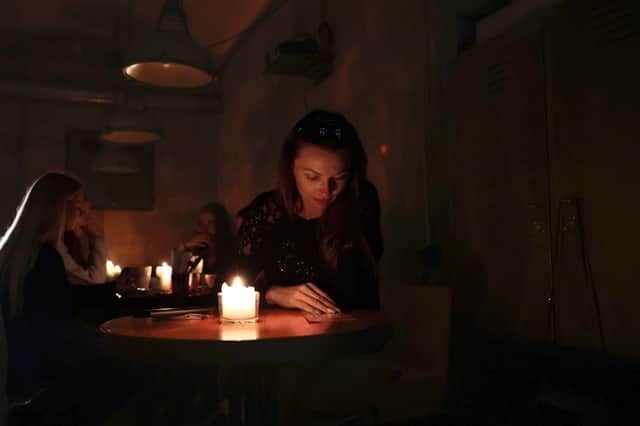 People sit in a café without power in Lviv, Ukraine. Once a safe haven for refugees, Russian attacks have plunged the city into darkness and cold (Picture: Jeff J Mitchell/Getty Images)