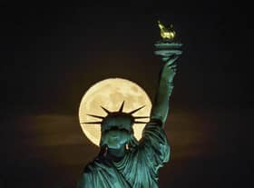 The Strawberry Supermoon rises in front of the Statue of Liberty in New York, late Tuesday, June 14, 2022. (AP Photo/J. David Ake)