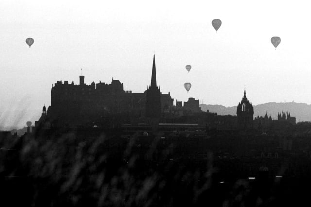 Hot air balloons rise from Holyrood Park silhouetted against the Edinburgh skyline, including Edinburgh Castle, in August 1984.