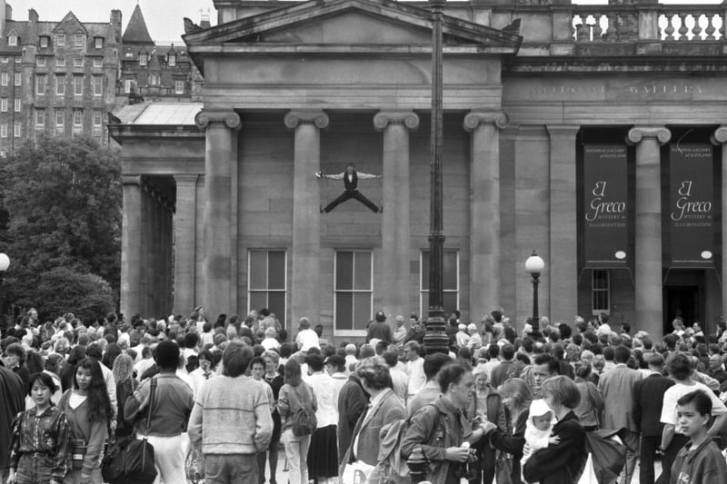 A street entertainer does a splits climb up the pillars of the  Royal Scottish Academy in Princes Street during Edinburgh Festival 1989.