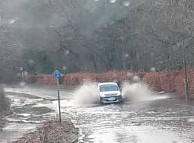A car ploughs through flood water near the Bush science park, Penicuik.