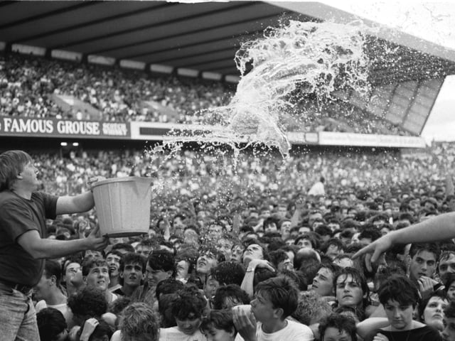 Stewards throw buckets of water to keep fans cool at the U2 concertat Murrayfield stadium Edinburgh, August 1987.