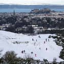 A view of Edinburgh Castle from The Braids with people sledging in the snow