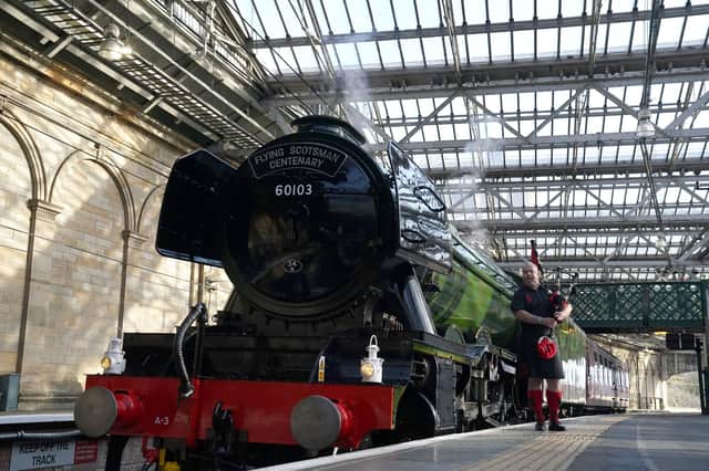Kevin MacDonald from the Red Hot Chilli Pipers beside Flying Scotsman at Edinburgh Waverley Station on Friday. Picture: Andrew Milligan/PA Wire
