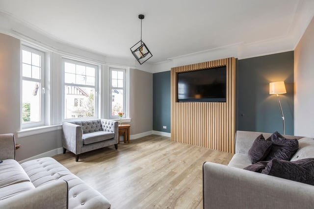 The elegant living room boasts a deep bay window offering fantastic views across the city skyline, along with Amtico flooring and a feature TV wall.