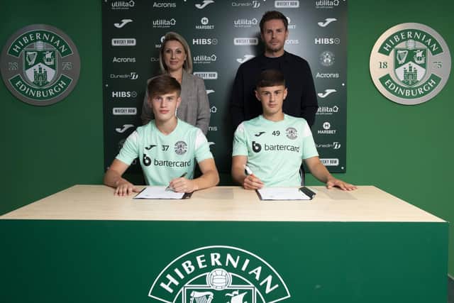 Oscar, left, and Jacob MacIntyre sign their new deals flanked by parents Stephanie and Boyd. Picture: Hibernian FC