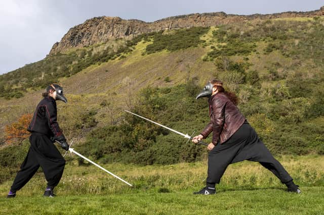 Andy and Charlotte Taylor from The Stork's Beak School of Historical Swordplay, Edinburgh, wear plague doctor masks and fight with longswords in Holyrood Park