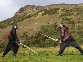 Andy and Charlotte Taylor from The Stork's Beak School of Historical Swordplay, Edinburgh, wear plague doctor masks and fight with longswords in Holyrood Park