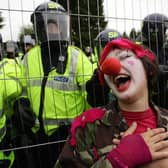 An anti-G8 protester dressed as a clown stands by a fence near Gleneagles hotel