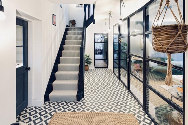 The dated wooden staircase and hallway floors were replaced with trendy, carpeted stairs and chic, black and white floor tiles.