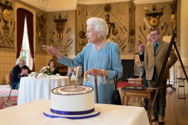 Queen Elizabeth II cuts a cake to celebrate the start of the Platinum Jubilee during the reception in the ballroom of Sandringham House, the Queen's Norfolk residence. (Photo by JOE GIDDENS/POOL/AFP via Getty Images)