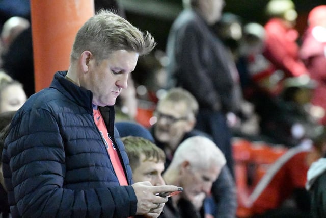 A Sunderland fan checks his phone whilst down at Crewe as his team ended the night in the top-two.