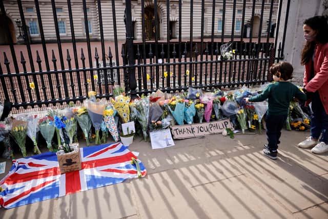 A well-wisher reflects at the floral tributes at the gates of The Palace of Holyroodhouse in Edinburgh (Photo by TOLGA AKMEN/AFP via Getty Images).