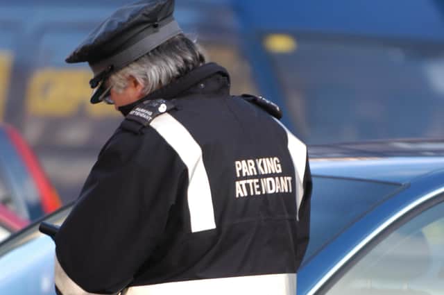 Parking attendant in Edinburgh writing a parking ticket