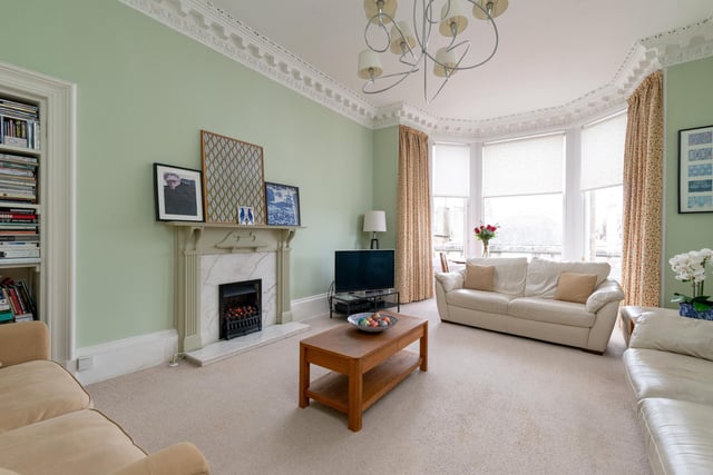 The property features this beautiful large living room, complete with desirable bay windows and high cornice celilings.