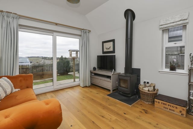 The living room is enhanced by a multi-fuel stove and rustic timber flooring.