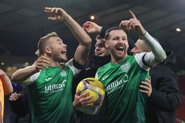 Hibs' Martin Boyle celebrates his hat-trick with the matchball and Ryan Porteous.