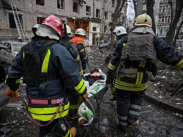 Ukrainian rescuers carry a wounded woman out of a damaged residential building in the centre of Kharkiv after a missile strike on January 2