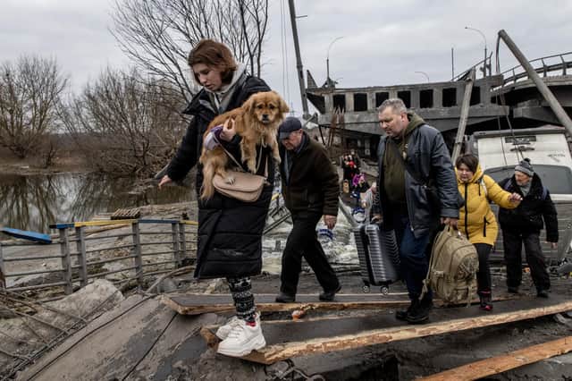 A woman carries her dog as she flees the fighting in the Ukrainian city of Irpin via a destroyed bridge (Picture: Chris McGrath/Getty Images)