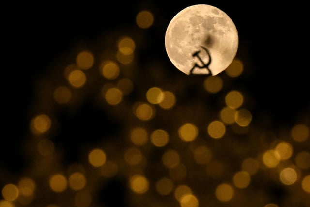 The Wolf Moon behind the Soviet symbol of hammer and sickle and Christmas and New Year's decorations in Moscow on January 7, 2023.