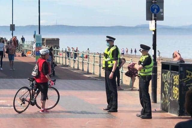 Two police officers speak to a cyclist at Portobello Beach.