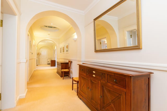 The entrance vestibule offers space for outerwear and opens into an exceptionally spacious hallway which provides access throughout the property, and features an ornate skylight window, carpeted flooring, uplights and recessed downlights.