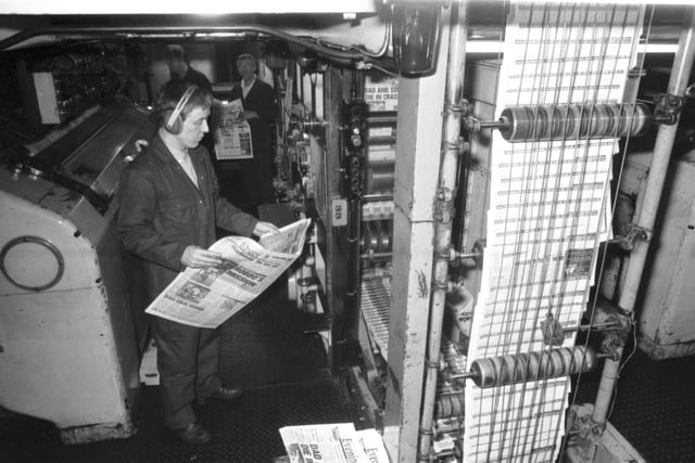 A Scotsman Publications employee wearing ear protectors checks a copy of the Evening News as it comes off the presses in the basement of the newspaper's headquarters at North Bridge Edinburgh, January 1990.