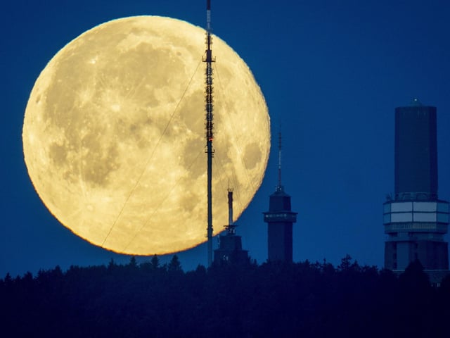 The full moon sets behind the telecommunication devices on top of the Feldberg mountain near Frankfurt, Germany, early Wednesday, June 15, 2022. (AP Photo/Michael Probst)
