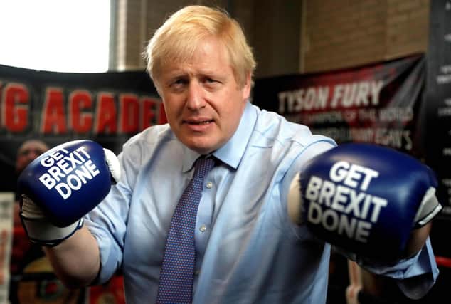 (FILES) In this file photo taken on November 19, 2019 Britain's Prime Minister and leader of the Conservative Party, Boris Johnson wears boxing gloves emblazoned with "Get Brexit Done" as he poses for a photograph at Jimmy Egan's Boxing Academy in Manchester north-west England on November 19, 2019, during a general election campaign trip. - Brexit becomes a reality on December 31, 2020 as Britain leaves Europe's customs union and single market, ending nearly half a century of often turbulent ties with its closest neighbours. The UK's tortuous departure from the European Union takes full effect when Big Ben strikes 11:00 pm (2300 GMT) in central London, just as the European mainland ushers in 2021 at midnight. Brexit has dominated British politics since the country's narrow vote to leave the bloc in June 2016, opening deep political and social wounds that still remain raw. (Photo by Frank Augstein / POOL / AFP) (Photo by FRANK AUGSTEIN/POOL/AFP via Getty Images)