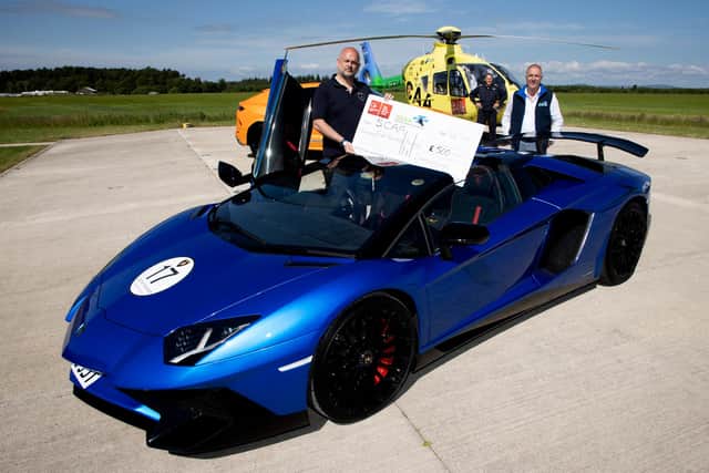 Andy Canning General Manager of Lamborghini Edinburgh pictured handing over a cheque for £500 to Nick Harvey Director of Fundraising & Communictaions at SCAA