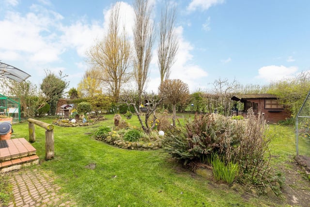 The rear garden is fully enclosed and has a lawn, flower beds and borders, wooden decking, water feature, a wooden deck with hot tub, large wooden summerhouse, wooden shed and greenhouse.