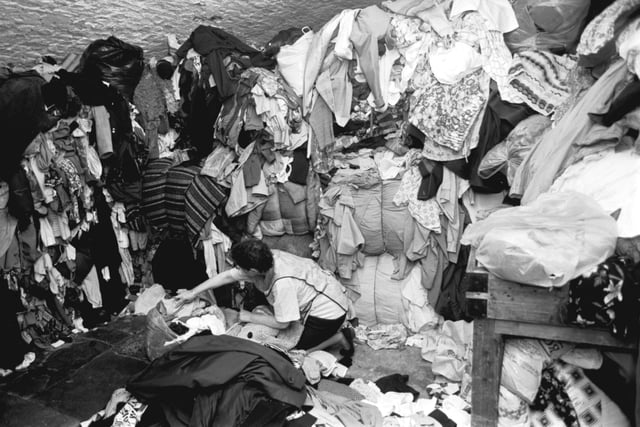 A female employee sorts through the bundles of used clothing at 'Nathan's Marine Stores', a rag shop in the Cowgate, Edinburgh, July 1988.