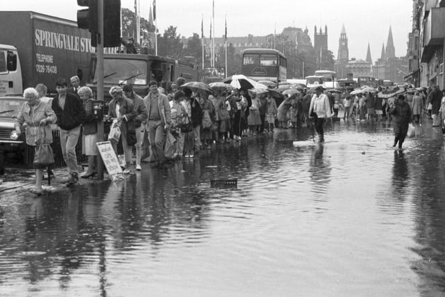 People walk around the large puddles on the pavement in Princes Street after flooding hit the city during heavy rain in July 1986.