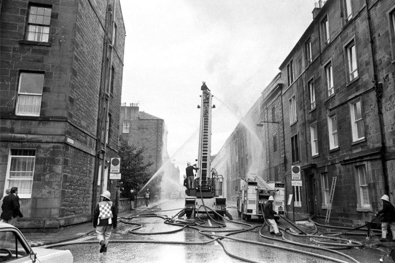 A fireman on a ladder directs water onto a fire at Bertrams' engineering works in Sciennes Edinburgh, September 1983.