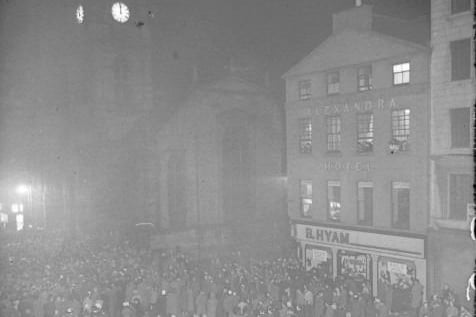 Hogmanay 1957: Revellers stand outside the Tron Kirk awaiting the stroke of midnight. The former Alexandra Hotel and B Hyam store can be seen on the right.