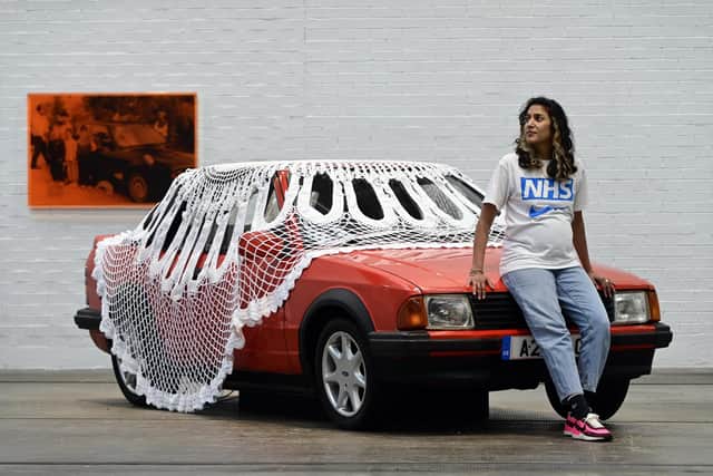 Artist Jasleen Kaur with her installation of a car covered in a giant doily