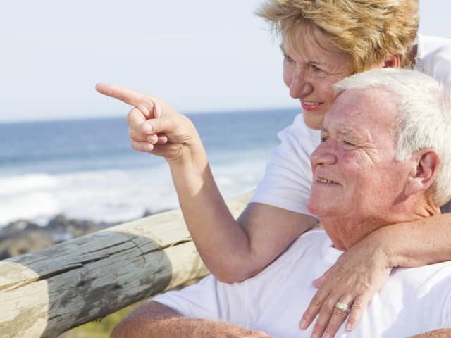 An elderly couple enjoy a visit to the beach