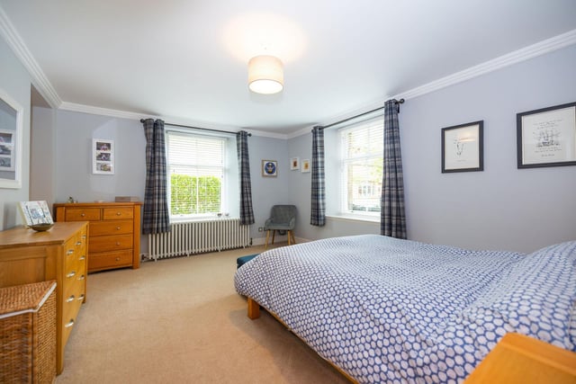 Principal double bedroom with a chic interior including carpeting and a cast iron radiator, a walk-in wardrobe, and a modern en-suite shower room.