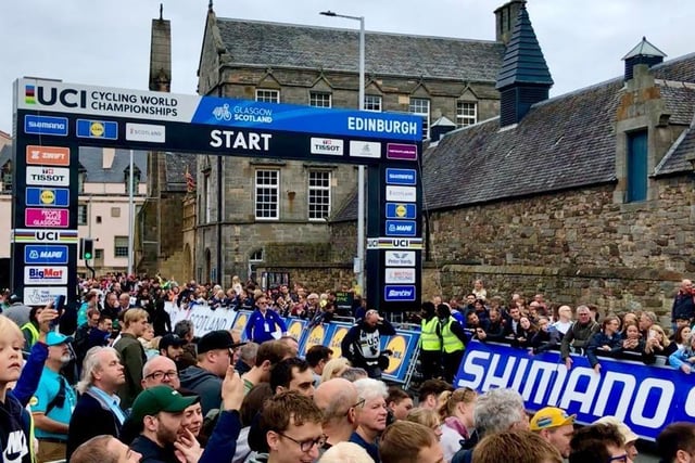 Spectators stand at the starting line to watch all the cyclists set off.