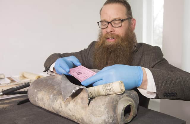 Consultant Conservator Nic Boyes  opens the 1898 time capsule discovered during the move of the Burns statue on Constitution Street, Leith, Edinburgh, for the tram works