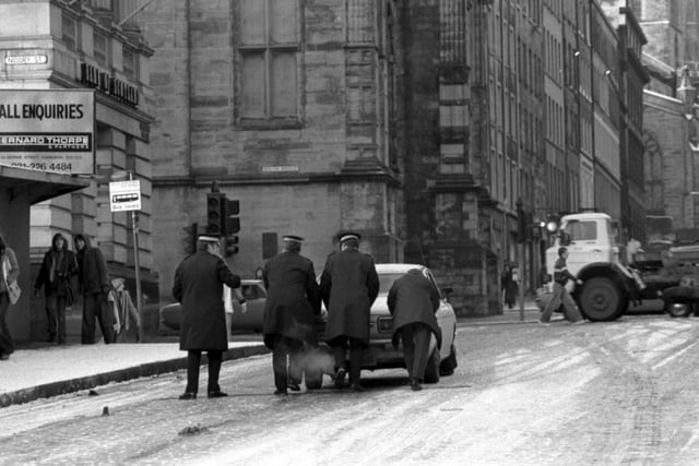 Policemen help a driver push his car through the snow up the Royal Mile in Edinburgh during the winter of 1978/1979.