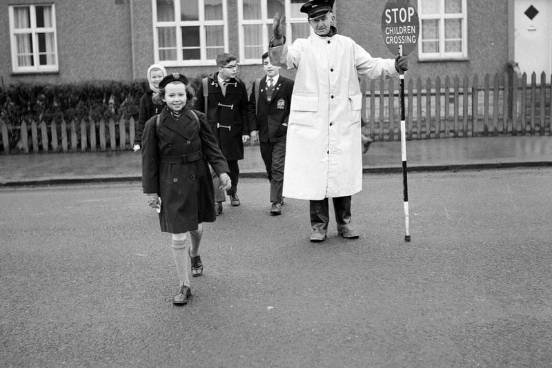 William Withnell, a traffic warden and lollipop man,  shows children across Colinton Mains Road to Oxgangs Primary School back in 1963.